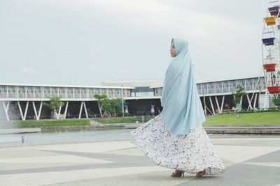 Woman with umbrella standing against the sky