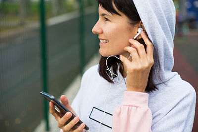 A caucasian woman uses a smartphone via wired headphones with a headset. phone in hand,