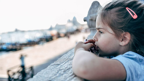 Side view of girl looking at beach against clear sky