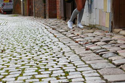 Low section of woman walking on cobblestone