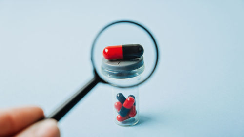 Covid pills concept. one red and black capsule with magnifying glass. covid-19 coronavirus drugs