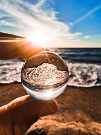 Close-up of water on beach against sky during sunset