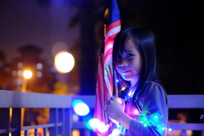 Portrait of smiling young woman using mobile phone at night