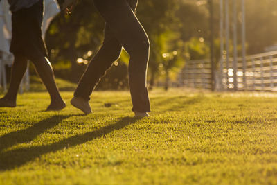 Low section of people walking on grassy field at park