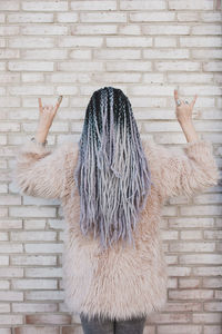 Rear view of woman walking against wall