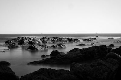 Rocks by sea against clear sky