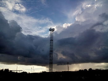 Low angle view of electricity pylon against cloudy sky