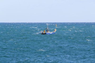 Boat sailing in sea against clear sky