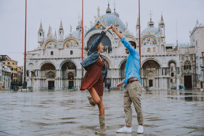 Young couple dancing against historic building