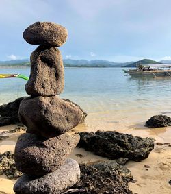 Stack of pebbles at beach against sky