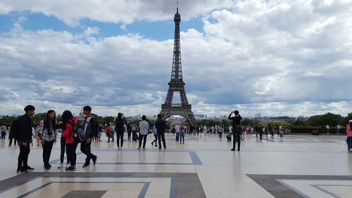 People at town square against cloudy sky