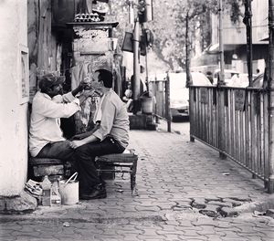 Barber shaving man beard on sidewalk