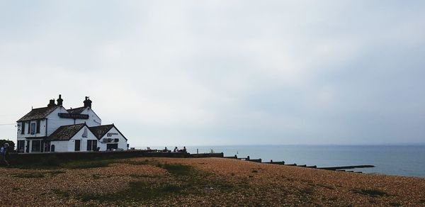 House on beach by sea against sky