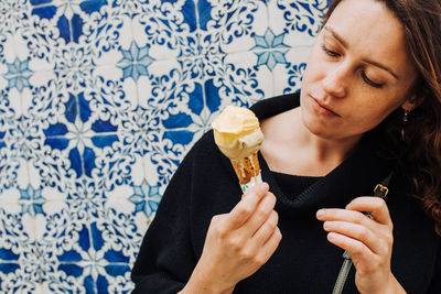 Millennial woman with freckles looking at melting ice cream