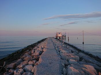 Pier by sea against sky during sunset