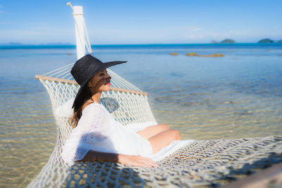 Woman sitting on beach against sea