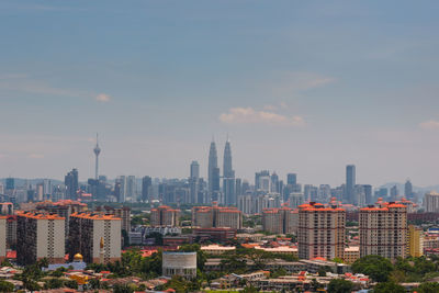 Petronas towers and kuala lumpur tower in city against sky