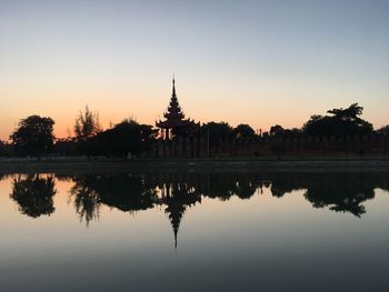 Reflection of silhouette trees in lake at sunset