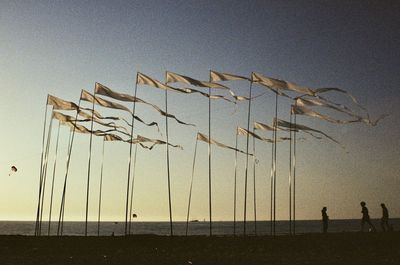 Low angle view of silhouette people on beach against clear sky