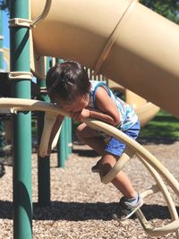 Full length of girl playing on outdoor play equipment at playground during sunny day