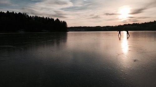 Reflection of trees in water at sunset