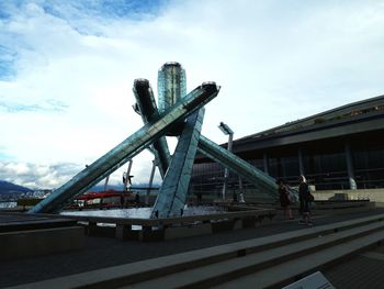 People on bridge by buildings against sky