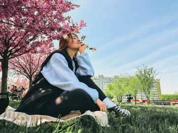 Young woman using mobile phone while sitting on field