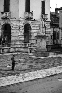 Rear view of woman walking on street by buildings in city