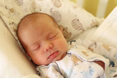 Close-up of cute baby girl sleeping on bed