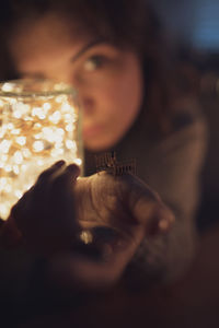 Portrait of woman holding illuminated lighting equipment in jar