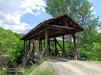 Old wooden bridge in forest against sky