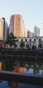 Reflection of buildings in city against clear sky