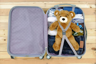 High angle view of teddy bear and clothes in suitcase