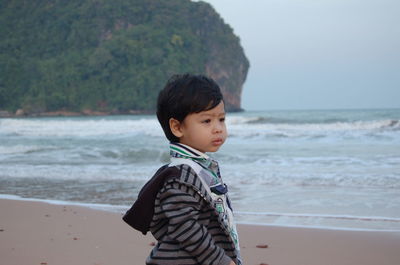 Boy standing at beach against sky