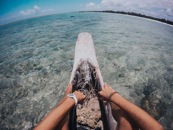 Low section of man sitting on log boat in sea