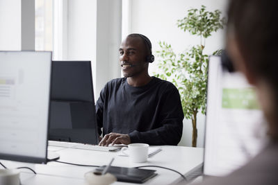 Smiling mature businessman using headset and desktop pc in office