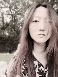 Portrait of beautiful young woman standing against tree