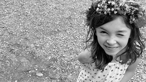 High angle portrait of cute smiling girl winking while standing on land