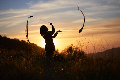 Woman juggling at sunset. she's in a nice meadow in the country.