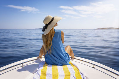 Rear view of woman in boat in sea against sky