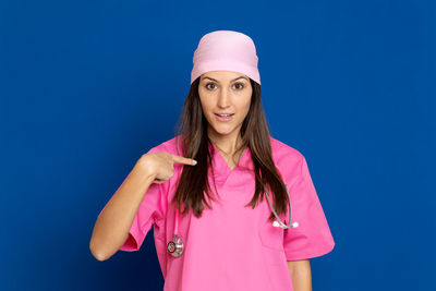 Portrait of smiling woman standing against blue background