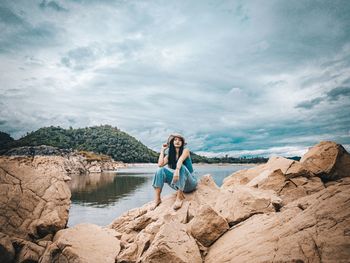 Full length of young woman on rock against sky