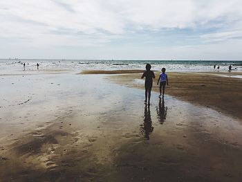 People walking on beach against sky