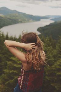 Rear view of woman standing by mountain against sky