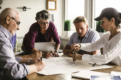 Elderly female instructor explaining senior men and woman over map during navigation course