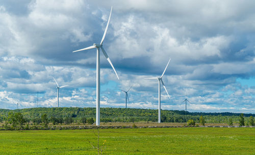 Windmills on field against sky