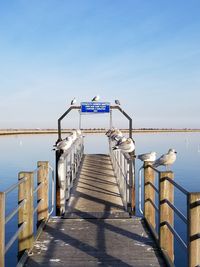 Pier over sea against clear blue sky