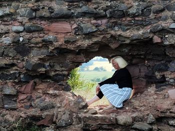 Side view full length of woman sitting on rock formation