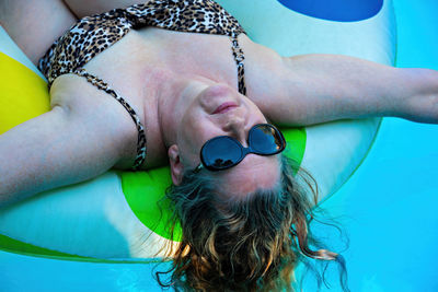 Close-up portrait of woman lying down in swimming pool