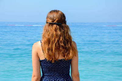 Rear view of woman standing at sea against sky